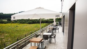 Een balkon met buitenmeubilair, een witte parasol en uitzicht op een groen veld.