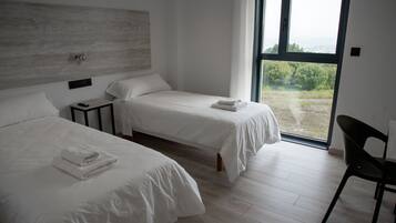 Un dormitorio moderno con dos camas, una mesita de noche y un ventanal que ofrece vistas al exterior.