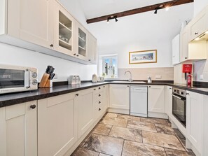 A kitchen with white cabinets, a microwave, a sink, and a dishwasher.