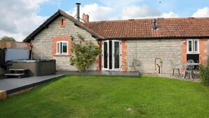 A stone house with a tiled roof, a hot tub, and a patio with outdoor furniture. - 2 bedroom accommodation in South Barrow, near Yeovil (South Barrow, near Yeovil)