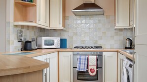 Una cocina moderna con gabinetes blancos, microondas, estufa y horno.