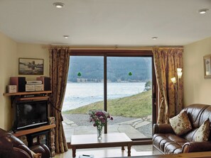 A living room with a large window, a television, a sofa, and a coffee table.