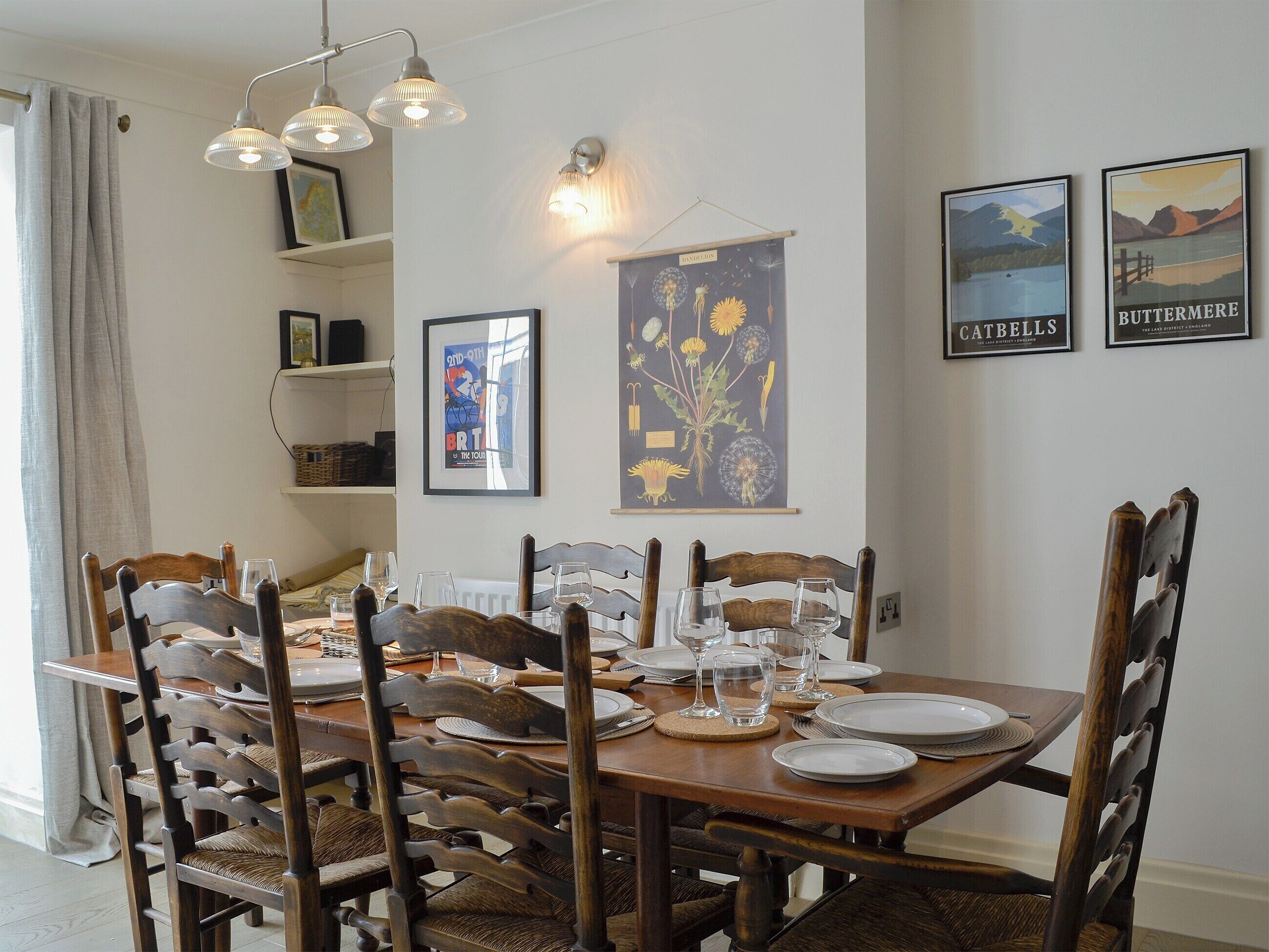 Un comedor con una mesa de madera dispuesta para cuatro personas, rodeada de sillas de madera con asientos de mimbre.