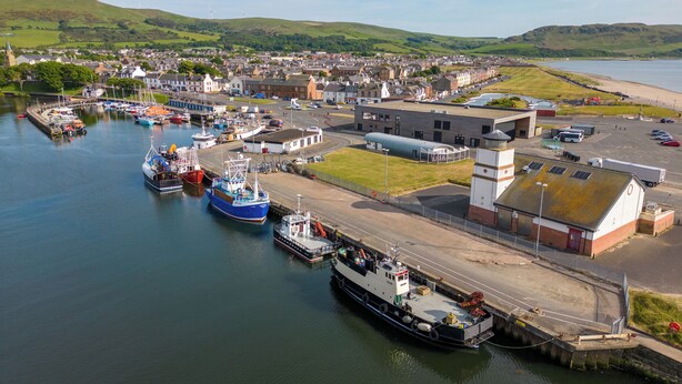 A harbor with boats, a building with a clock tower, and a town in the background. - 2 bedroom accommodation in Girvan (Girvan)