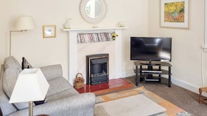 A living room with a sofa, a television, a fireplace, and a rug. - 2 bedroom accommodation in Girvan (Girvan)
