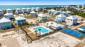 Un complejo turístico costero con varias edificaciones tipo bungaló, una piscina central y canchas de tenis.