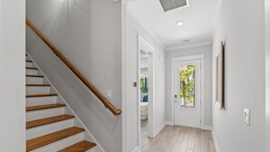 Una escalera de madera con barandilla que lleva a una puerta con un panel de vidrio.