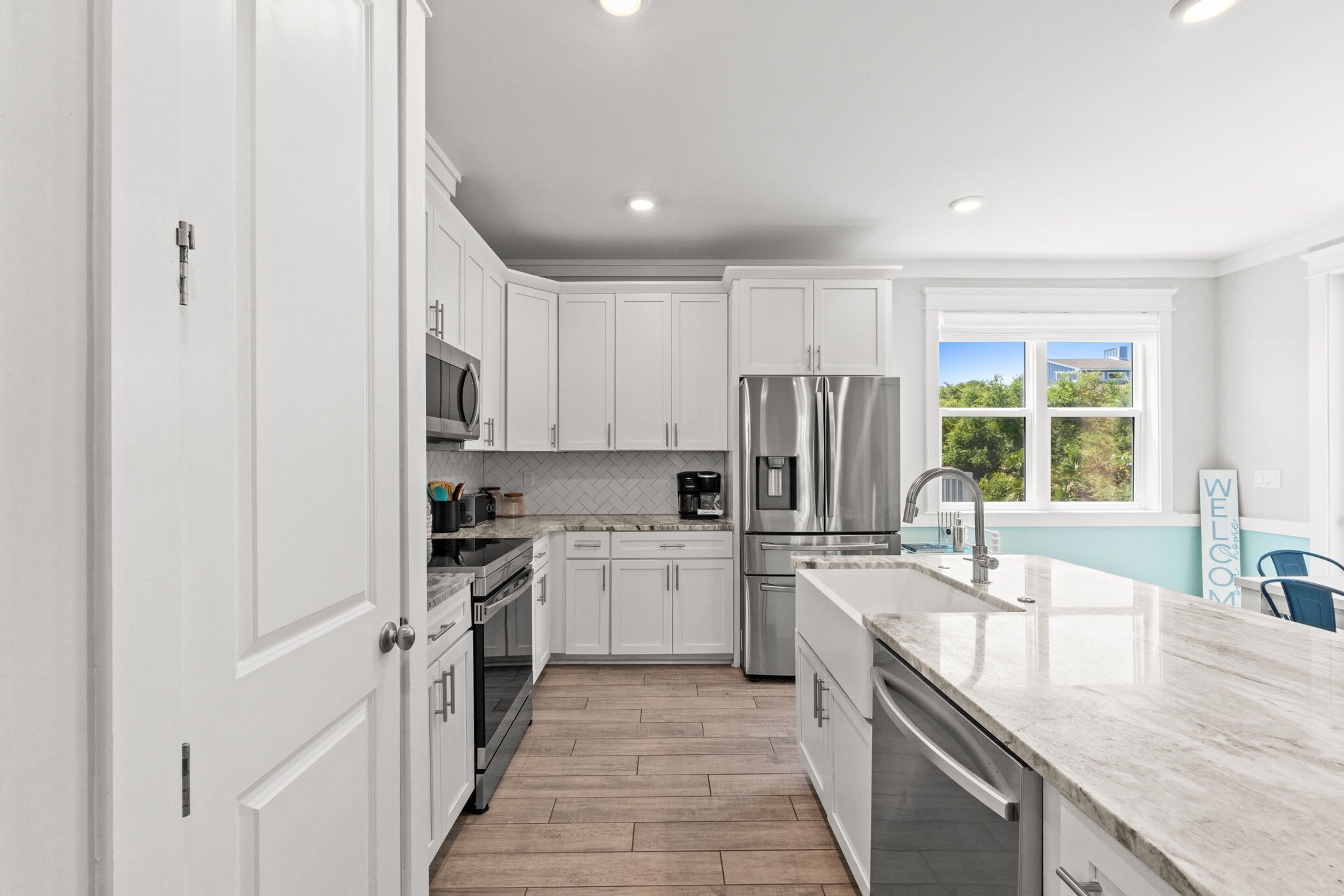 A modern kitchen with white cabinets, stainless steel appliances, and a large island with a sink.