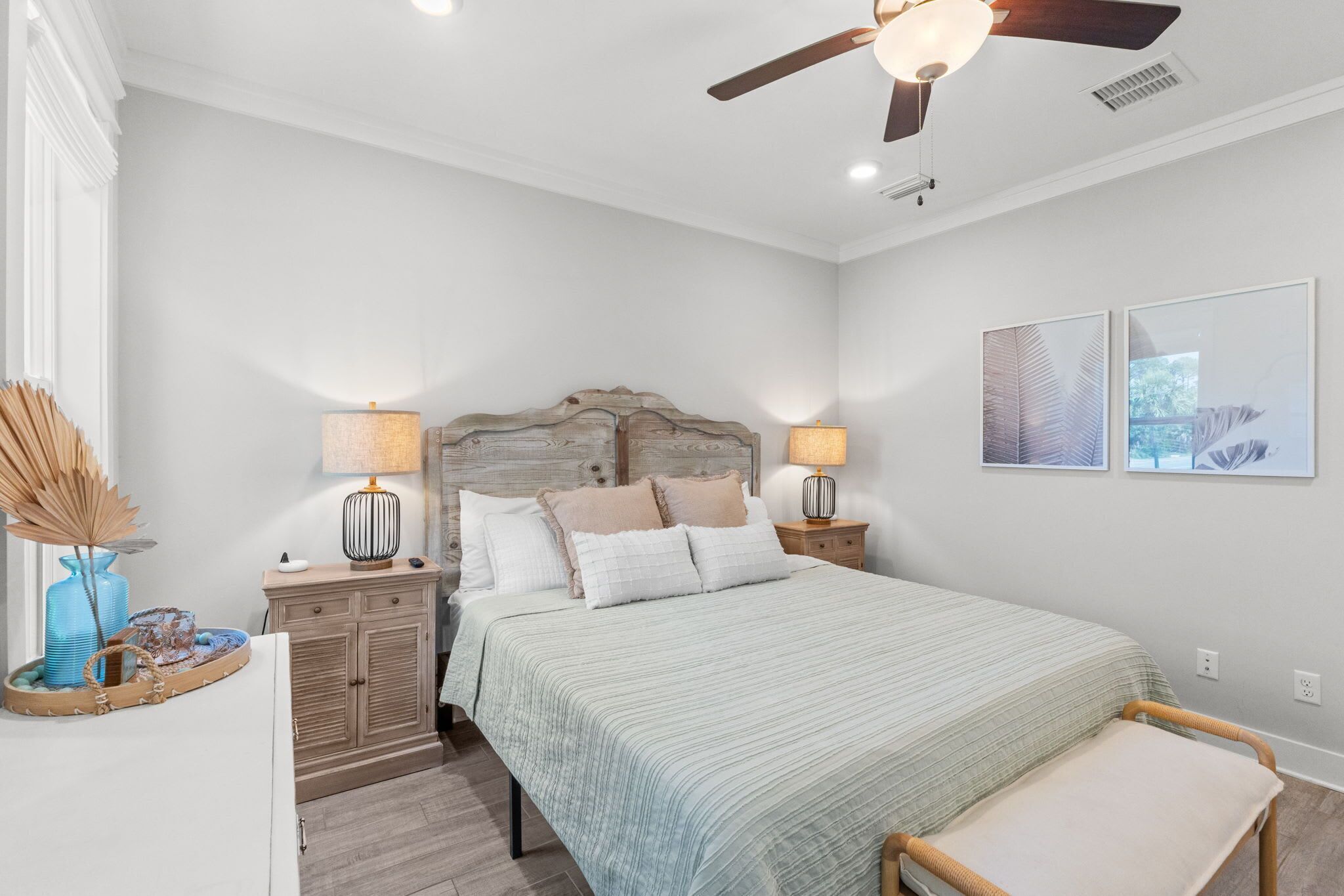 A bedroom with a bed, two bedside tables, a ceiling fan, and two wall-mounted lamps.