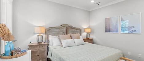 A bedroom with a bed, two bedside tables, a ceiling fan, and two wall-mounted lamps.
