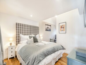 A bedroom with a bed, bedside tables, a nightstand, a chair, and artwork on the walls.