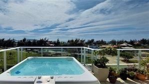Uma banheira de hidromassagem numa varanda com vista para uma área residencial e montanhas ao longe.