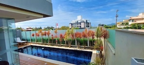 Una piscina con vistas a un edificio moderno y un muro verde con plantas.