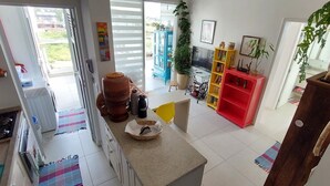Uma cozinha com uma janela grande, uma estante vermelha e um vaso de planta.