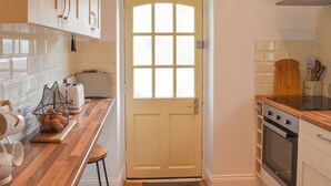 Una cocina con encimera de madera, un tostador, una tetera y una estufa.
