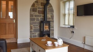 Una habitación con chimenea de piedra, muebles de madera, un televisor y una ventana con persianas.