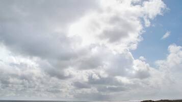 A beach with a grassy foreground and a cloudy sky.