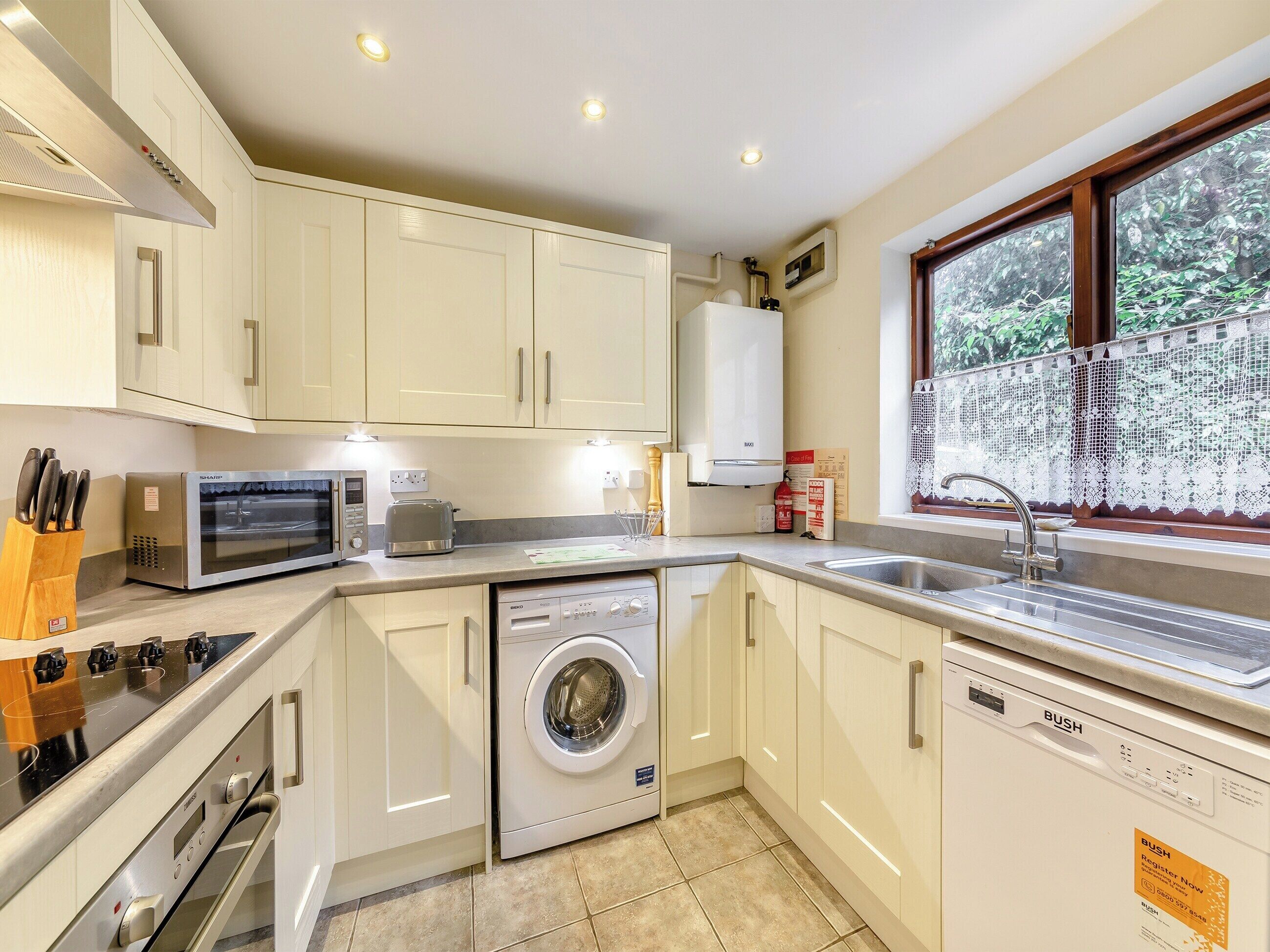 A compact kitchen with white cabinets, a microwave, toaster, washing machine, and dishwasher.