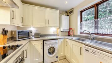 A compact kitchen with white cabinets, a microwave, toaster, washing machine, and dishwasher.