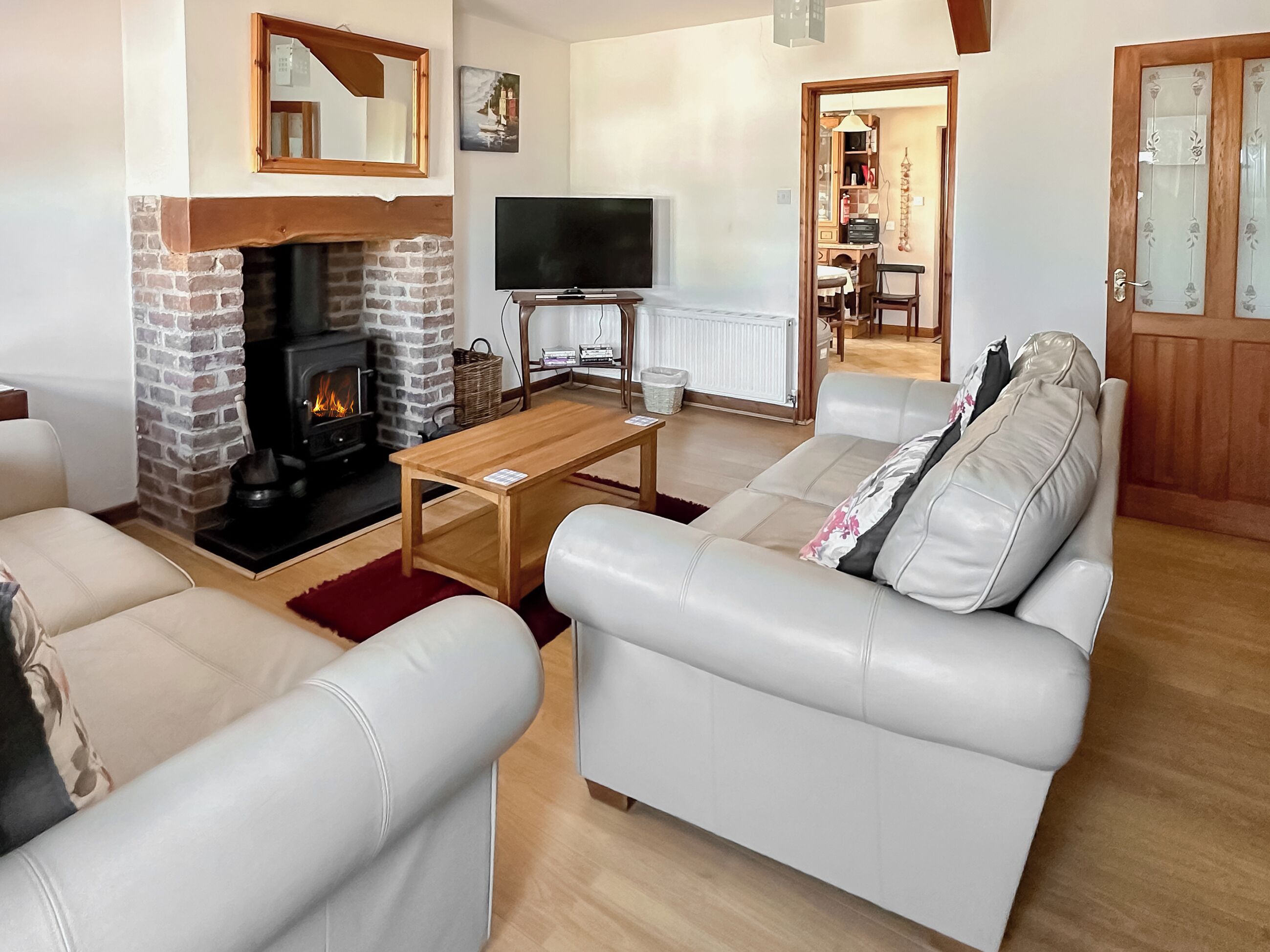 A living room with a fireplace, a television, a sofa, and a dining area.