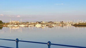 A marina with numerous boats docked, a clear sky, and a blue railing in the foreground. - Converted barn set on a working farm with plenty of walks from the door. (Abererch, near Pwllheli)
