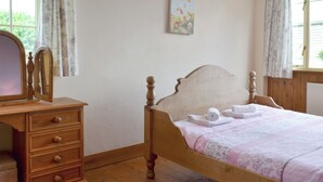 A bedroom with a wooden bed, a dresser with drawers, a mirror, and a painting on the wall.