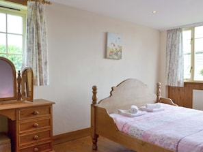 Ein Schlafzimmer mit einem hölzernen Bett, einer Kommode mit Schubladen, einem Spiegel und einem Bild an der Wand.
