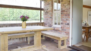 A wooden table with benches, a brick wall, a window, and a door.