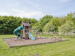 Un parque infantil con tobogán, zona de escalada y mesas de picnic.