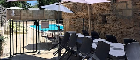 An outdoor patio with a pool, stone walls, and outdoor seating.