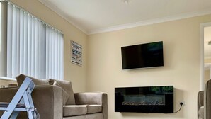 A living room with a beige sofa, a flat-screen TV, and a fish tank.