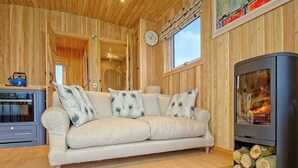 Een gezellige woonkamer met een bank, een open haard en houtopslag.