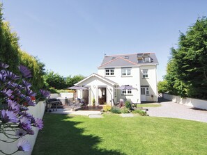 A two-story house with a front porch, a small garden, and a driveway.