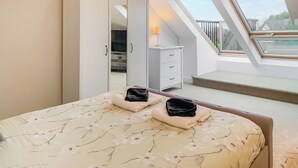 Une chambre à coucher avec un lit, une armoire, un bureau et une fenêtre de toit.