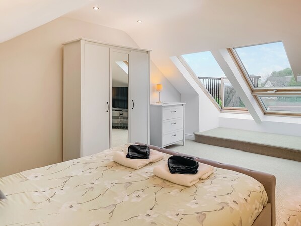 A bedroom with a bed, a wardrobe, a desk, and a skylight.