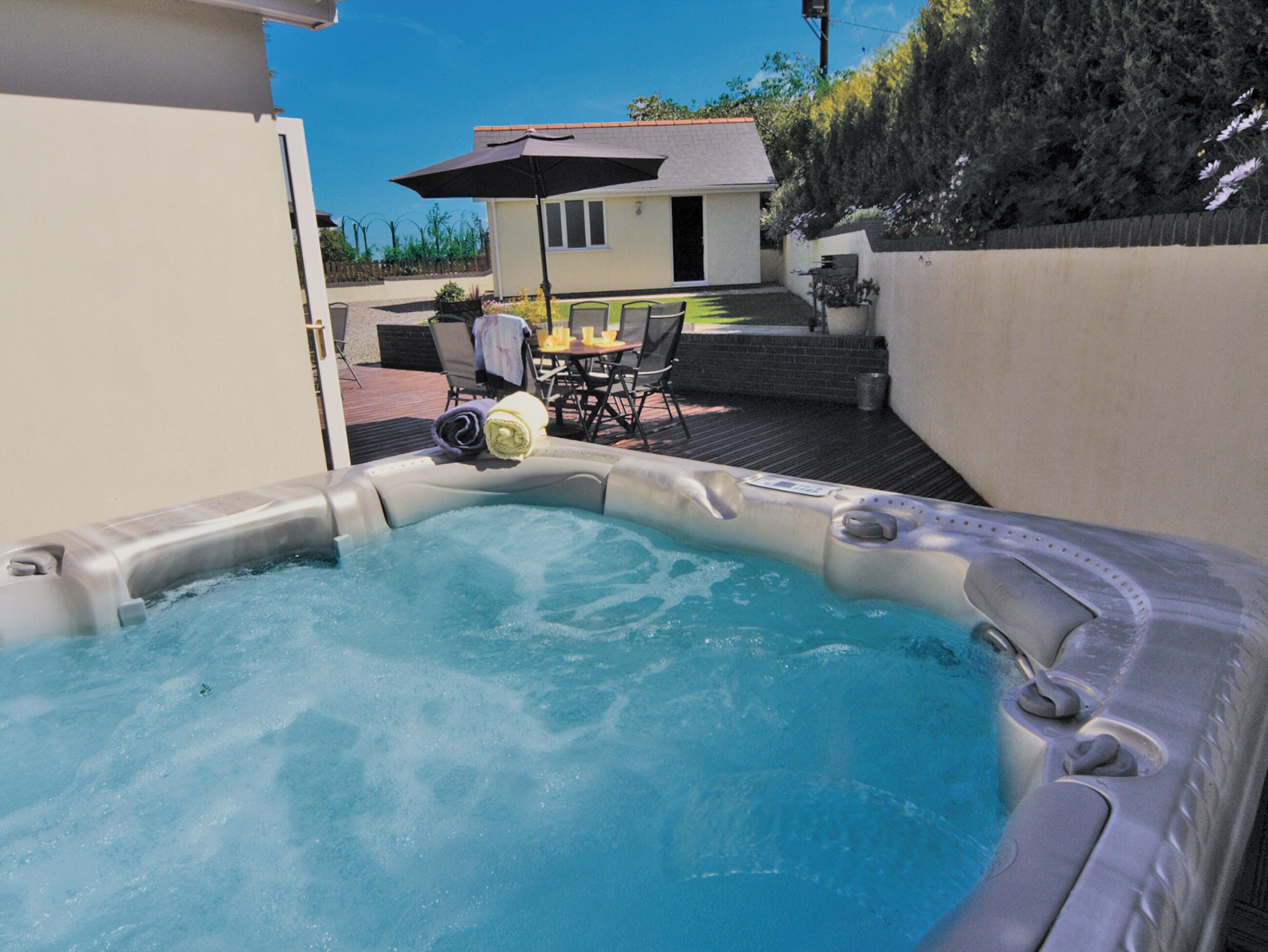 A hot tub with a view of a house and patio furniture.