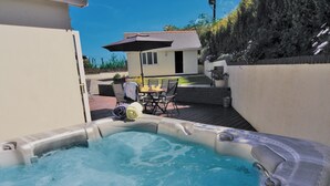 Un bain à remous avec vue sur une maison et sur du mobilier de jardin.
