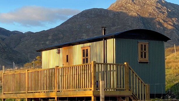 En træhytte med balkon, med et bjergrigt landskab i baggrunden.