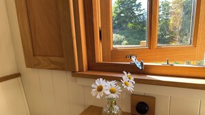 Et træskab med et vindue over og en radiator under, samt en vase med blomster på et træbord.