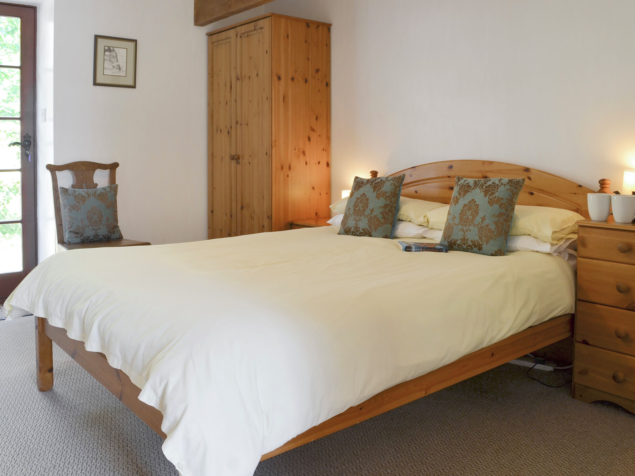 Une chambre à coucher avec un lit en bois, une table de chevet, une commode et une armoire.