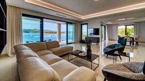 A modern living room with a large sofa, a coffee table, and a view of the sea. - Villas Anita (Zadar)