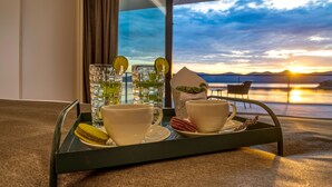 A tray with two cups and macarons on a carpeted floor, with a scenic sunset view through a window. - Villas Anita (Zadar)