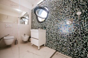 A modern bathroom with a bidet, a vanity with a mirror, and a mosaic-tiled shower wall. - Villas Anita (Zadar)