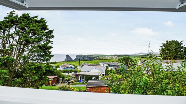 A coastal view from a window overlooking houses and greenery. - 1 bedroom accommodation in Bossiney, near Tintagel (Bossiney, near Tintagel)