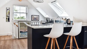 A modern kitchen with a central island, white bar stools, and skylights. - 1 bedroom accommodation in Bossiney, near Tintagel (Bossiney, near Tintagel)