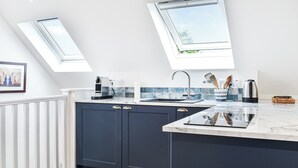 A modern kitchen with dark cabinets, a white countertop, a skylight, and a view of greenery outside. - 1 bedroom accommodation in Bossiney, near Tintagel (Bossiney, near Tintagel)