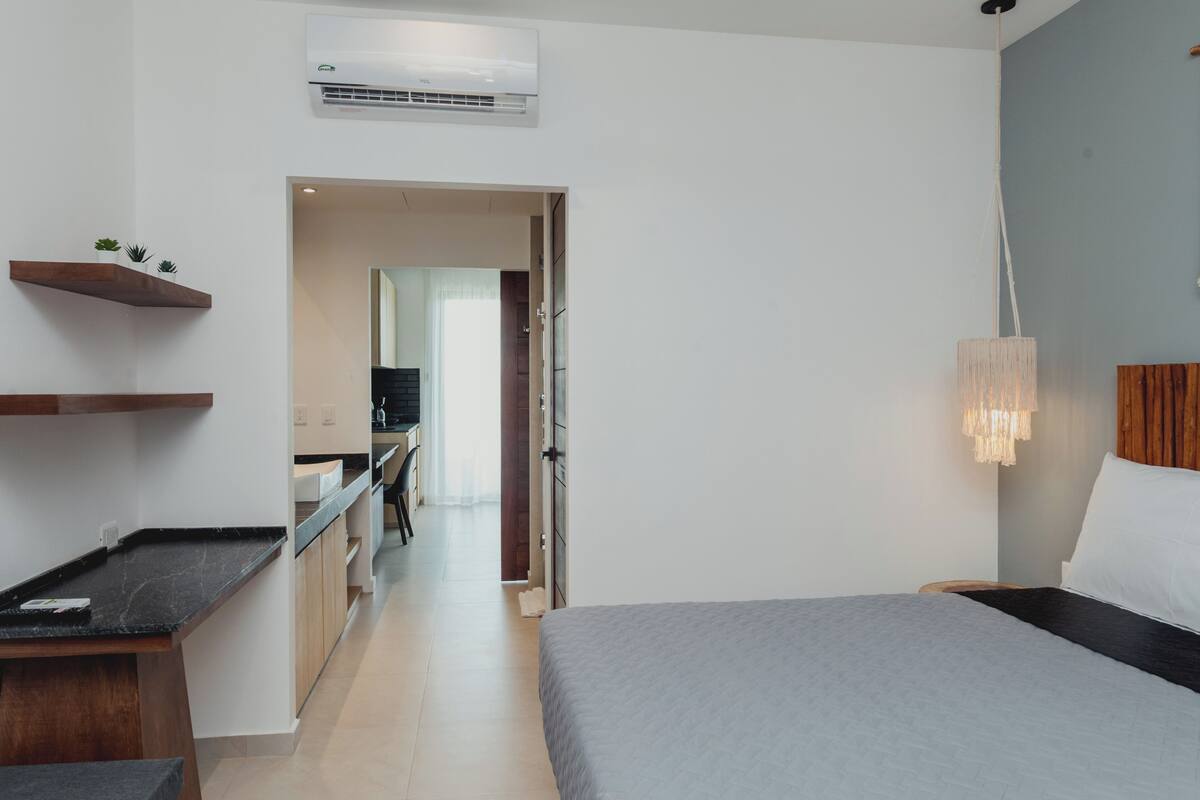 Habitación de hotel moderna con cama, mesita de noche y lámpara colgante.