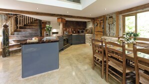 A spacious kitchen with a central island, a dining area with wooden furniture, and a staircase leading to an upper level. - 4 bedroom accommodation in Longhope, near Gloucester (Longhope, near Gloucester)