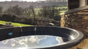 A hot tub with a view of a green landscape and a house in the background. - 4 bedroom accommodation in Longhope, near Gloucester (Longhope, near Gloucester)