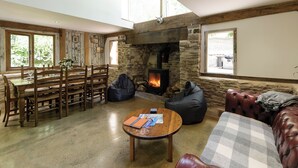 A spacious living area with a stone fireplace, wooden furniture, and large windows. - 4 bedroom accommodation in Longhope, near Gloucester (Longhope, near Gloucester)